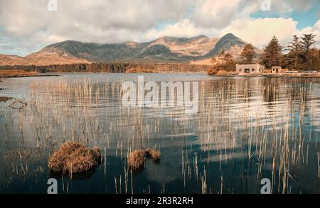 Wunderschöne Landschaft mit Haus am See mit Bergen im Hintergrund im Lough Inagh, connemara Nationalpark, County Galway, Irland Stockfoto