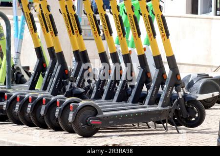 Woosh E-Scooter, die in einer Regimentsschlange geparkt und in Lissabon, Portugal, gemietet werden. Andere E-Scooter-Marken sind ebenfalls erhältlich, ebenso wie E-Bikes. Stockfoto