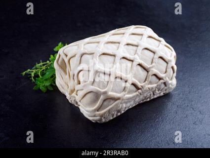 Rohes Kasseler-Schweinesteak in Blätterteig, Nahaufnahme auf einem schwarzen Brett mit Kräutern Stockfoto