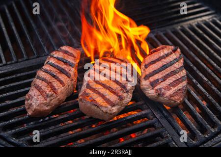 Grillen Sie trocken gereiftetes angus-Sirloin-Beefsteak, das als Nahaufnahme auf einem Holzkohlegrill mit Feuer und Rauch gegrillt wird Stockfoto