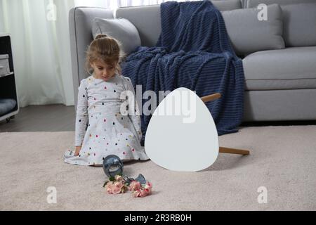 Kind und zerbrochene Keramikvase auf dem Boden zu Hause Stockfoto