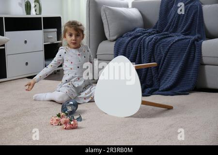 Kind und zerbrochene Keramikvase auf dem Boden zu Hause Stockfoto