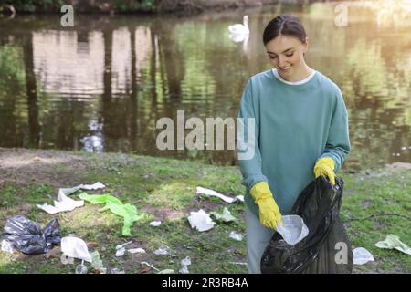 Junge Frau mit Plastiktüte, die Müll im Park sammelt Stockfoto