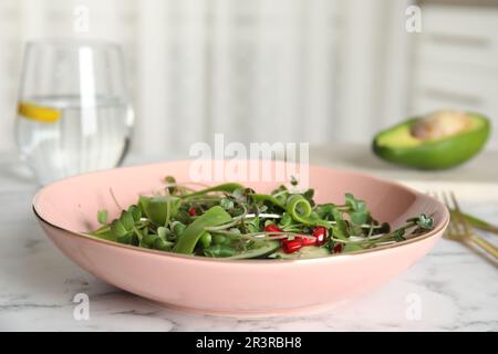 Salat mit frischen Bio-Mikrogreens in der Schüssel auf weißem Marmortisch im Innenbereich Stockfoto