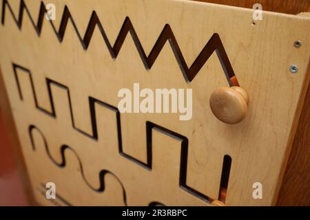 Ein hölzernes Labyrinth mit verschiedenen Linien an der Wand, Nahaufnahme. Montessori Spielzeug Stockfoto