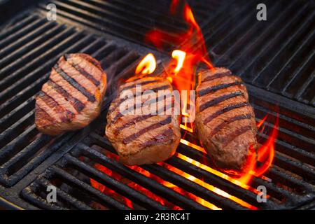 Grillen Sie trocken gereiftetes angus-Sirloin-Beefsteak, das als Nahaufnahme auf einem Holzkohlegrill mit Feuer und Rauch gegrillt wird Stockfoto