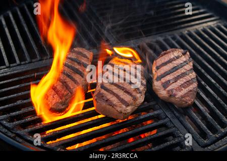 Grillen Sie trocken gereiftetes angus-Sirloin-Beefsteak, das als Nahaufnahme auf einem Holzkohlegrill mit Feuer und Rauch gegrillt wird Stockfoto