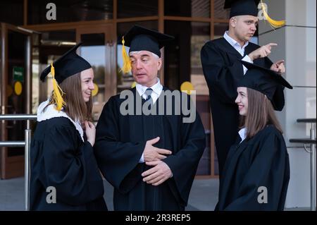 Klassenkameraden in Abschlusskleidern. Barrierefreie Bildung für alle Altersgruppen. Stockfoto