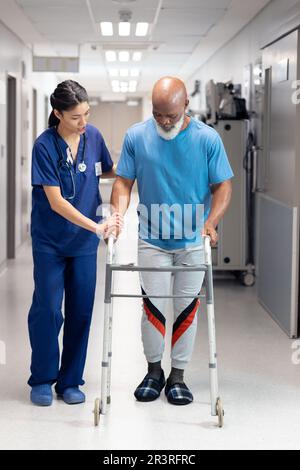 Vertikal einer vielseitigen Ärztin, die ältere männliche Patienten mit Laufrahmen und Kopierraum unterstützt Stockfoto