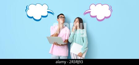 Aufmerksames junges Paar mit Laptops und leeren Sprechblasen auf hellblauem Hintergrund Stockfoto