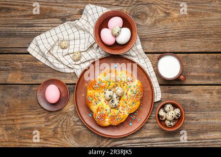 Zusammensetzung mit leckerem italienischen Osterbrot, Eiern und Milch auf Holzhintergrund Stockfoto