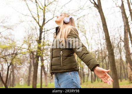 Entspannte Frau mit Kopfhörern, die frische Luft atmet und im Park Musik hört Stockfoto