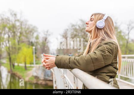 Entspannte Frau mit Kopfhörern, die frische Luft atmet und im Park Musik hört Stockfoto