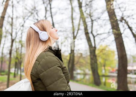 Entspannte Frau mit Kopfhörern, die frische Luft atmet und im Park Musik hört Stockfoto