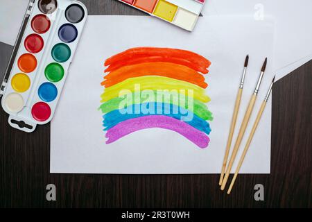 Pinsel, Farben und weißes Blatt Papier mit farbenfrohem Regenbogen Stockfoto