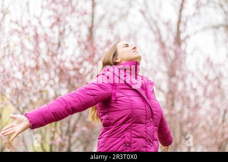 Entspannte Frau mit Kopfhörern, die frische Luft atmet und im Park Musik hört Stockfoto