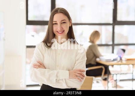 Eine fröhliche Managerin steht mit gekreuzten Armen im Amt Stockfoto