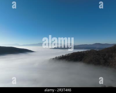 Luftaufnahme. Fliegen Sie über die hohen Berge in wunderschönen Wolken. Drohnen-Kamera aus der Luft. Luftverschmutzungswolken über Sarajevo Stockfoto