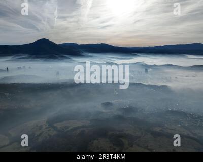 Luftaufnahme. Fliegen Sie über die hohen Berge in wunderschönen Wolken. Drohnen-Kamera aus der Luft. Luftverschmutzungswolken über Sarajevo Stockfoto