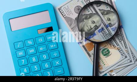 Blauer Taschenrechner und ein Stapel US-Dollar-Scheine auf blauem Hintergrund Stockfoto