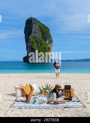 Koh Poda Beach Krabi Thailand, ein paar Männer und Frauen am Strand Picknick mit Obst und Getränken Stockfoto