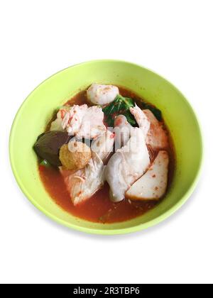 Gestanzte Yentafo Fish Ball Noodles in einer grünen Schüssel in rosafarbener Suppe auf weiß isoliert. Stockfoto