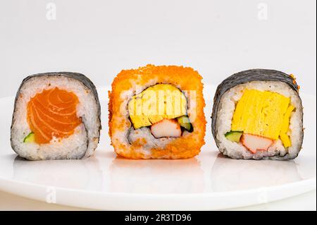 Verschiedene hausgemachte japanische Sashimi-Sushi-Brötchen, Nori-Seetang, Lachsfisch, in weißer Keramikplatte isoliert auf weißem Hintergrund. Stockfoto