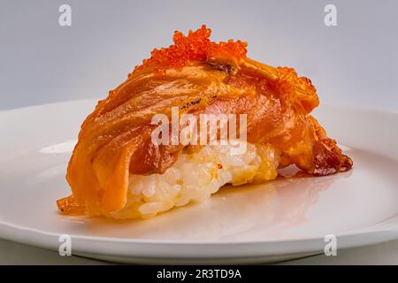 Seitenansicht von frischem hausgemachtem Sushi mit Fisch und Fischeiern auf weißer Keramikplatte isoliert auf weißem Hintergrund, Nahaufnahme. Stockfoto