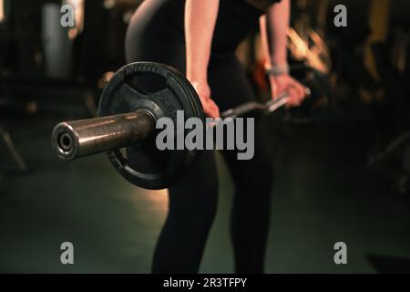 Eine Frau in schwarzen Leggings trainiert im modernen Fitnesscenter Barbell Fitness. Gewichtheben, Krafttraining, Sportliebhaber Stockfoto