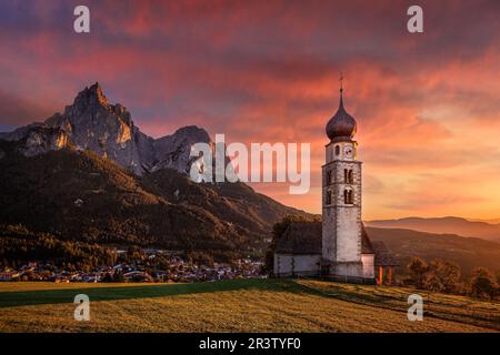 Seis am Schlern, Italien - berühmter St. Die Kirche Valentin und der berühmte Berg Sciliar mit spektakulärem farbenfrohen Sonnenuntergang im Herbst und idyllischer Berglandschaft Stockfoto