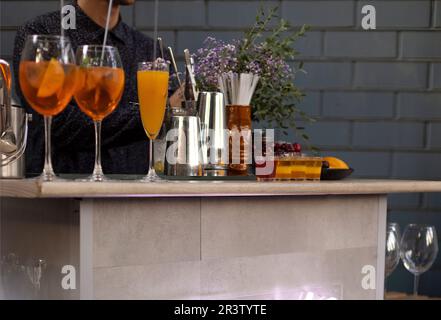 Gläser Cocktails an der Bar. Der Barkeeper schenkt ein Glas Sekt mit rotem Alkohol ein. Stockfoto