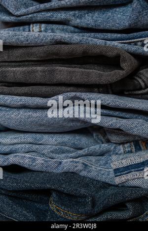 Abstrakter Jeanenstapel. Hintergrund Mode Jeans strukturiert verschiedene Farbtöne Denim. Leinwand Denim Textur. Blaues Denim Closeup Stockfoto