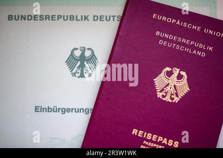 Berlin, Deutschland. 22. Mai 2023. Auf einem Tisch liegen ein Einbürgerungszeugnis der Bundesrepublik Deutschland (l) und ein deutscher Pass. Ausländer in Deutschland werden demnächst die deutsche Staatsbürgerschaft leichter erlangen können, so die Pläne der Bundesregierung. Kredit: Fernando Gutierrez-Juarez/dpa/Alamy Live News Stockfoto