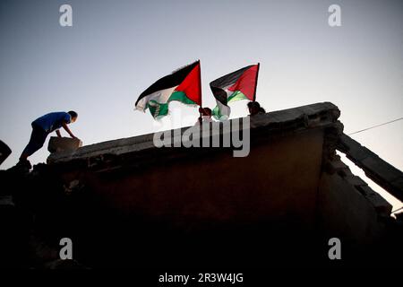 Gaza-Stadt, Palästina. 24. Mai 2023. Palästinensische Kinder hissen die Flagge Palästinas auf den Ruinen ihres zerstörten Hauses nach israelischen Angriffen auf die Stadt Beit Lahiya im nördlichen Gazastreifen. Israel und der Islamische Dschihad haben Ende Mai 13 einen Waffenstillstand unter ägyptischer Vermittlung vereinbart. Israel hat mehrere Angriffe auf die militärische Führung des islamischen palästinensischen Dschihad verübt. Gazastreifen, 24. Mai 2023. Foto: Habboub Ramez/ABACAPRESS.COM Kredit: Abaca Press/Alamy Live News Stockfoto