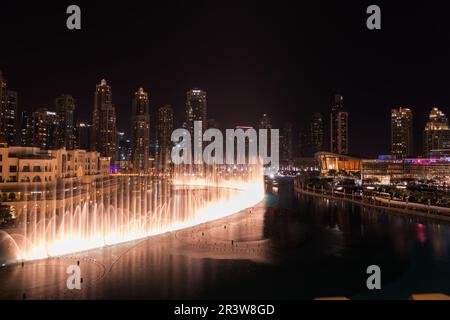 Dubai singende Brunnen bei Nacht Seeblick zwischen Wolkenkratzern. Moderne Architektur in der Dämmerung der Skyline der Stadt in der Innenstadt der Vereinigten Arabischen Emirate Stockfoto