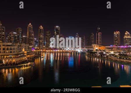 Dubai singende Brunnen bei Nacht Seeblick zwischen Wolkenkratzern. Moderne Architektur in der Dämmerung der Skyline der Stadt in der Innenstadt der Vereinigten Arabischen Emirate Stockfoto