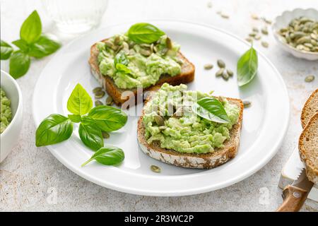 Avocado-Sandwich mit Kürbiskernen. Gesunder vegetarischer Avocado Toast mit Roggenbrot zum Frühstück. Vegane Speisekarte Stockfoto