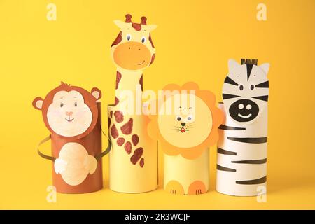 Spielzeugaffe, Giraffe, Löwe und Zebra aus Toilettenpapier auf gelbem Hintergrund. Handgemachte Kinderideen Stockfoto