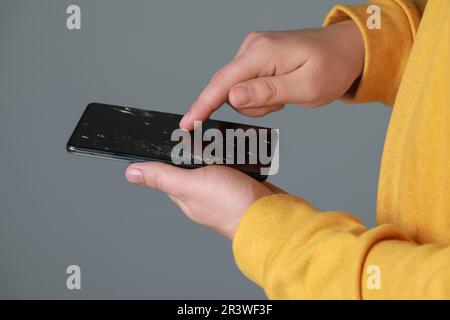Mann hält beschädigtes Smartphone auf hellgrauem Hintergrund, Nahaufnahme. Gerät wird repariert Stockfoto