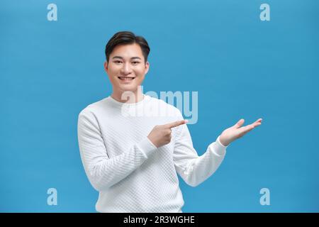 Aufgeregter, glücklicher junger Student, der mit Fingern und Handgesten auf Werbeartikel zeigt, Stockfoto