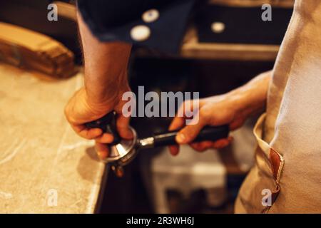 Barista mahlt frisch geröstete Kaffeebohnen aus einem professionellen, modernen elektrischen Mahlwerk zu einem Pulver Stockfoto