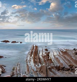 Twilight Ozean Küste mit geripptem stratiform Rock. Stockfoto