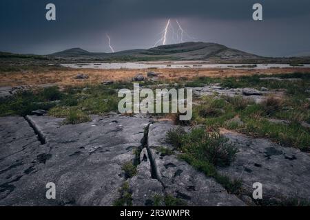 Dramatische bewölkte Landschaft mit Gewitter über den Bergen am See im Burren National Park in County Clare, Irland Stockfoto