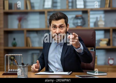 Porträt eines wütenden jungen Geschäftsmanns, der im Büro mit Kunden, Team und Partnern telefoniert. Unzufrieden mit der Arbeit, knapper Terminkalender, Entlassung aus einem Job. Stockfoto