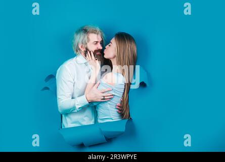 Paar in Liebe Kuss in Loch Papier Hintergrund. Rabatt und Verkauf. Geküsste Paar bärtige Mann und glückliche Frau machen Loch in Papier Kuss durch Loch Stockfoto