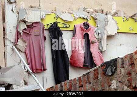 OKHTYRKA, UKRAINE - 24. MAI 2023 - Kleidung hängt an der Wand eines Gebäudes im Stadtzentrum, das durch russische Bomben beschädigt wurde, Okhtyrka, Sumy Region, Norden Stockfoto