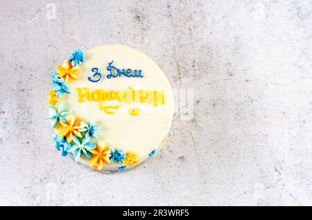Trendiger Bento-Kuchen mit blau-gelber Aufschrift „Happy Birthday“ in der Ukraine auf hellem Hintergrund. Geburtstagskuchen, Bento-Kuchen für zwei Ukrai Stockfoto