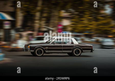 Panning-Aufnahme eines sich bewegenden braunen chevrolet Caprice auf der Straße Stockfoto