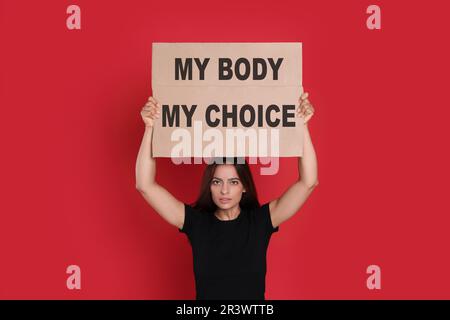 Frau mit Plakat und Phrase My Body My Choice auf rotem Hintergrund. Schwangerschaftsabbruch-Protest Stockfoto