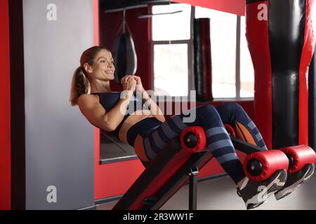 Eine Frau, die bauchmuskeln auf einem römischen Stuhl im Fitnessstudio aufpumpt Stockfoto